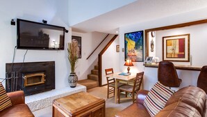 A living room with a fireplace, a television, a dining area with a table and chairs, and a staircase. - 31sw - Fireplace - Wifi - Washer/dryer - Sleeps 4 2 Bedroom Home by RedAwning (Deming)