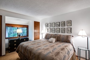 Relax in a spacious bedroom with a large bed, dresser, and nightstand, surrounded by framed city views.