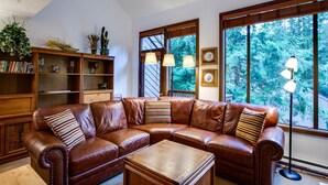 A living room with a brown leather sectional sofa, a wooden coffee table, and a bookshelf filled with books and decorative items. - 31sw - Fireplace - Wifi - Washer/dryer - Sleeps 4 2 Bedroom Home by RedAwning (Deming)