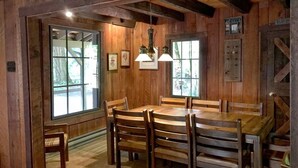A rustic wooden dining room with a large table and chairs, large windows, and hanging light fixtures. - 31sw - Fireplace - Wifi - Washer/dryer - Sleeps 4 2 Bedroom Home by RedAwning (Deming)
