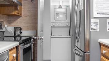 A compact kitchen with a built-in washer-dryer unit, a microwave, and a refrigerator.