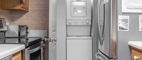 A compact kitchen with a built-in washer-dryer unit, a microwave, and a refrigerator.