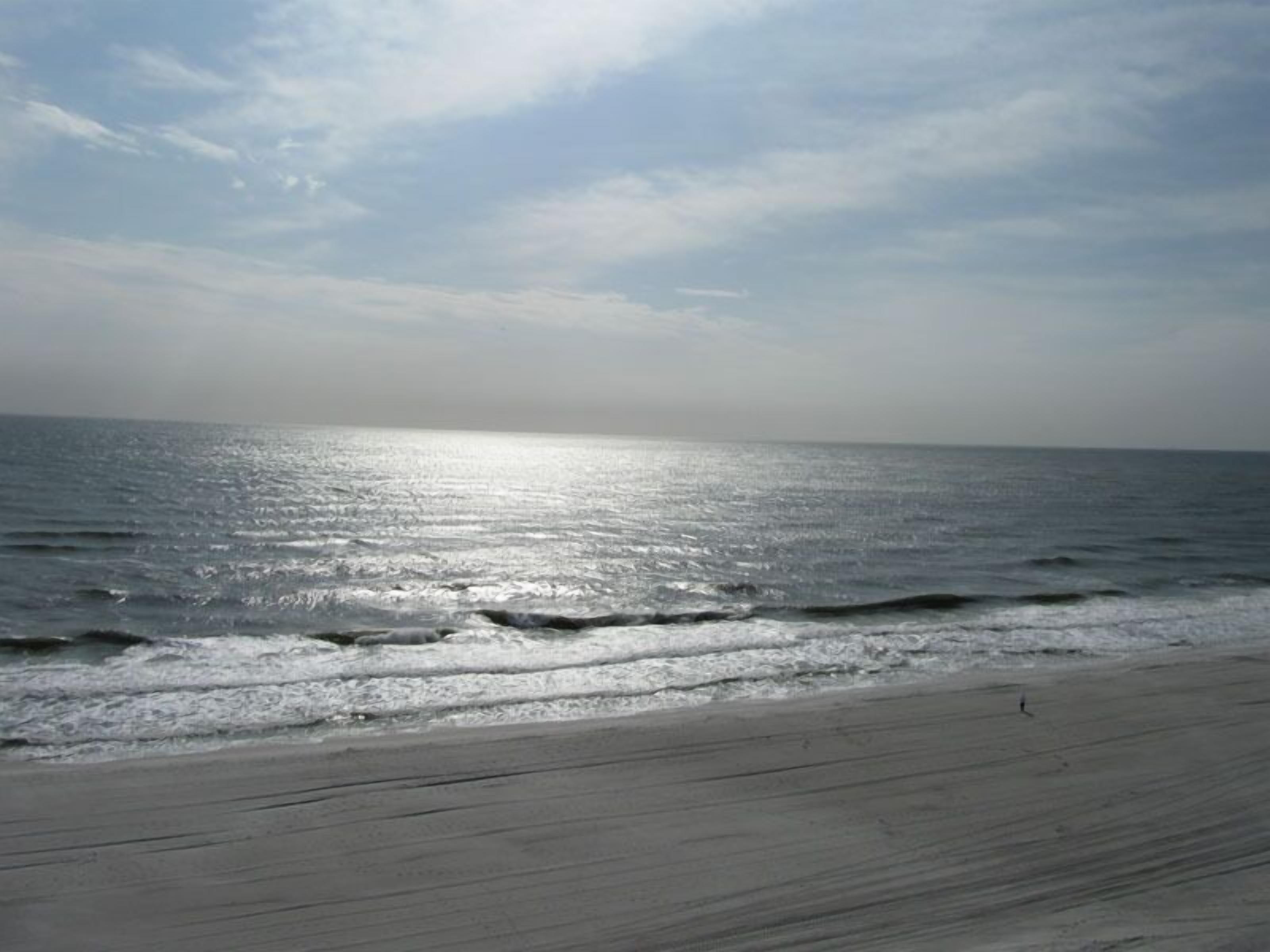 A beach with a wooden walkway leading to the water.