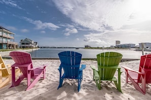 A beach with colorful Adirondack chairs and a view of the water. - The Pelican 4 Bedroom Home by RedAwning (Gulf Shores)