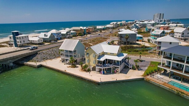 Un quartier résidentiel situé sur la côte, avec des maisons à proximité de la plage, un pont et une vue sur l’océan.