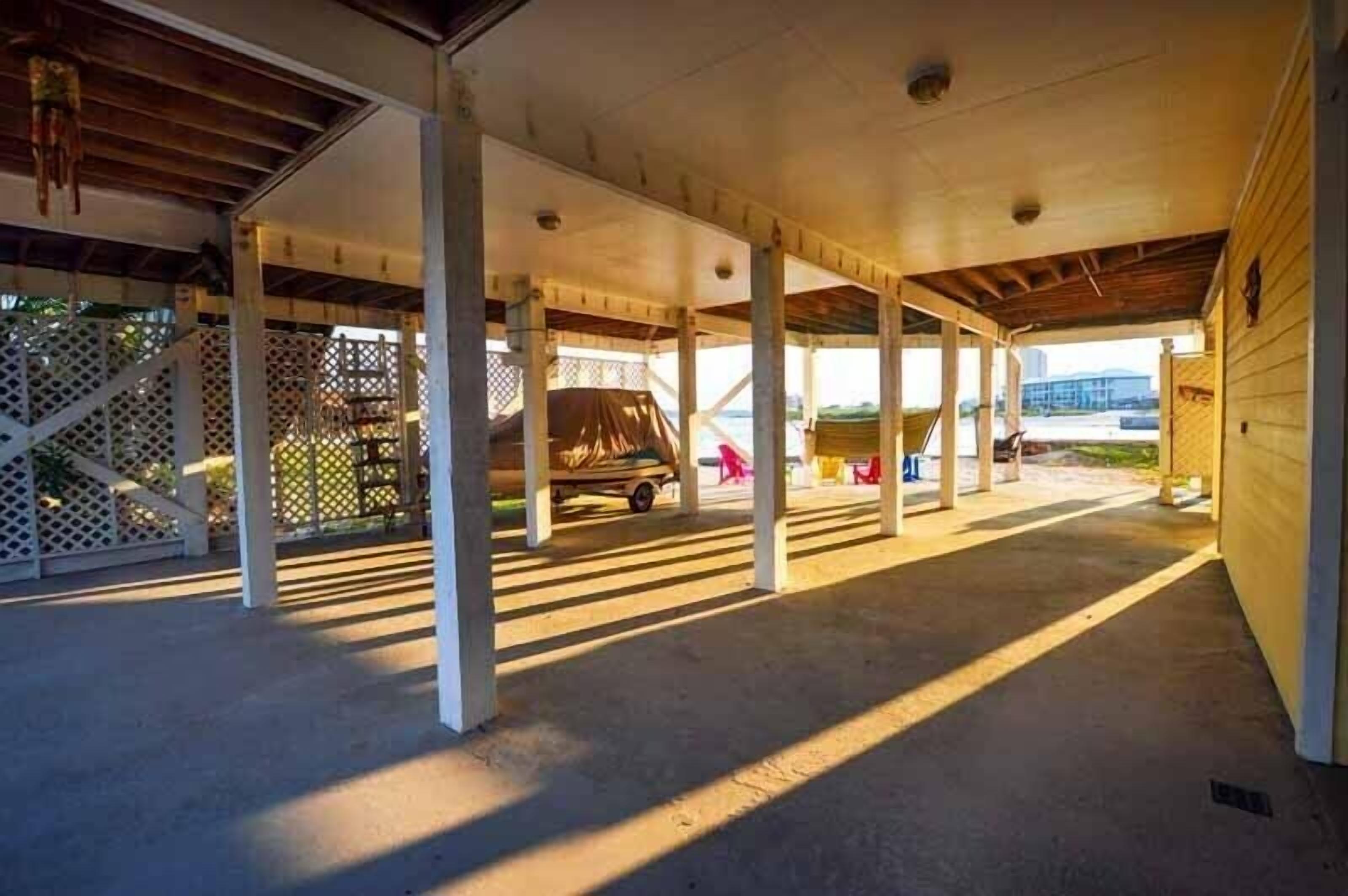 A covered parking area with a vehicle, columns, and a fence.