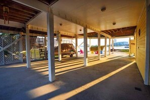A covered parking area with a vehicle, columns, and a fence. - The Pelican 4 Bedroom Home by RedAwning (Gulf Shores)