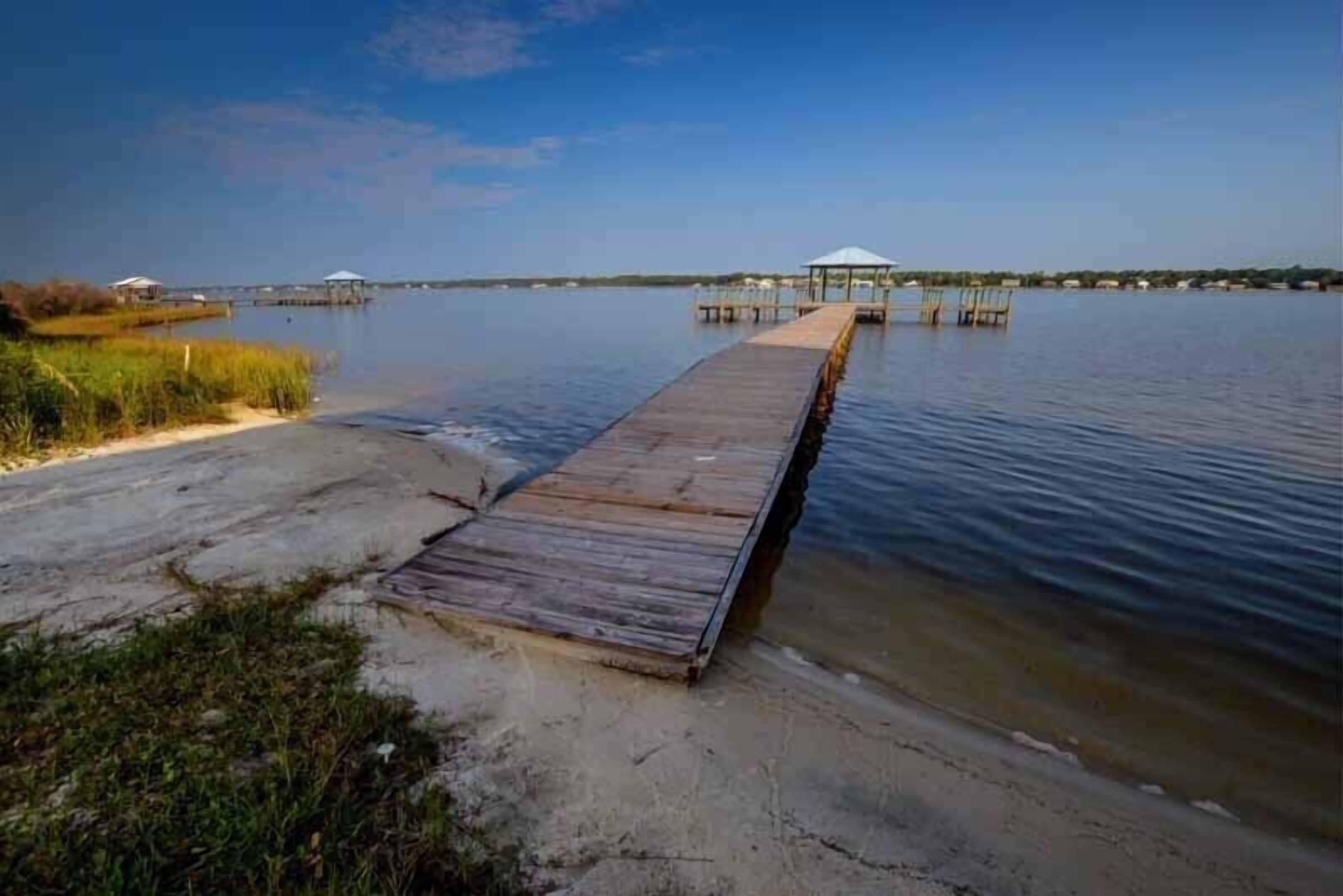 Un muelle de madera que se adentra en aguas tranquilas, con un pabellón al final.