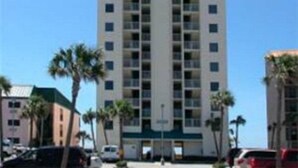 A multi-story hotel with a central atrium, palm trees, and a clear blue sky.