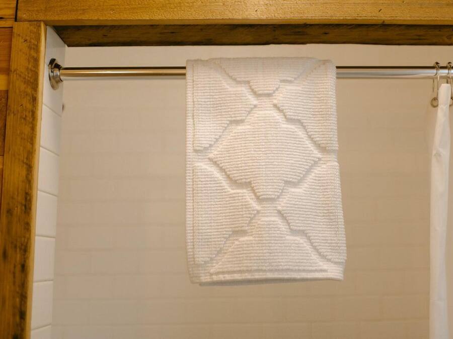 A bathroom with a wooden ceiling, a towel hanging on a metal rod, and a white shower curtain.