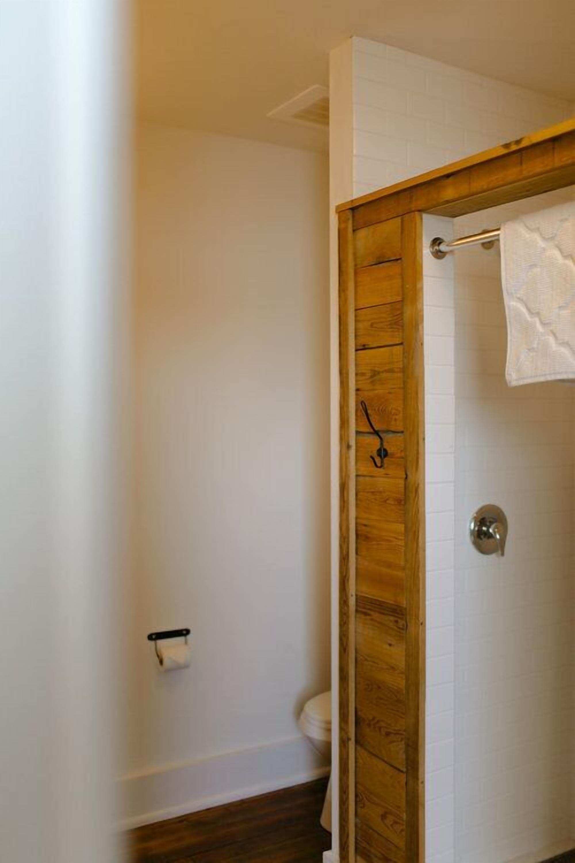 A bathroom with a wooden door, a towel hanging on a rack, and a toilet.
