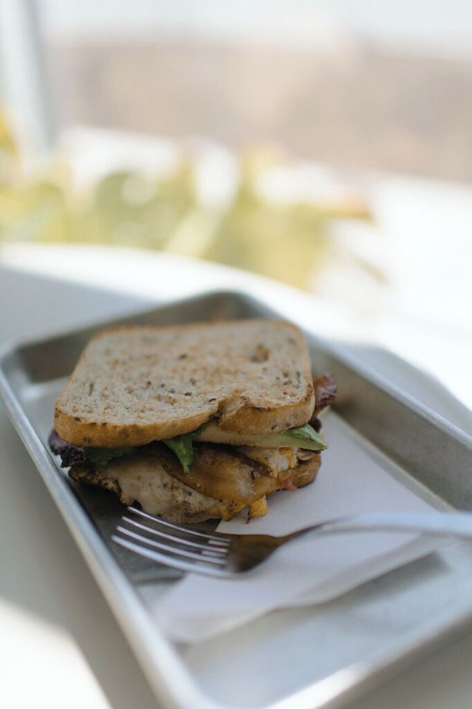 A sandwich on a tray with a fork, placed on a table.