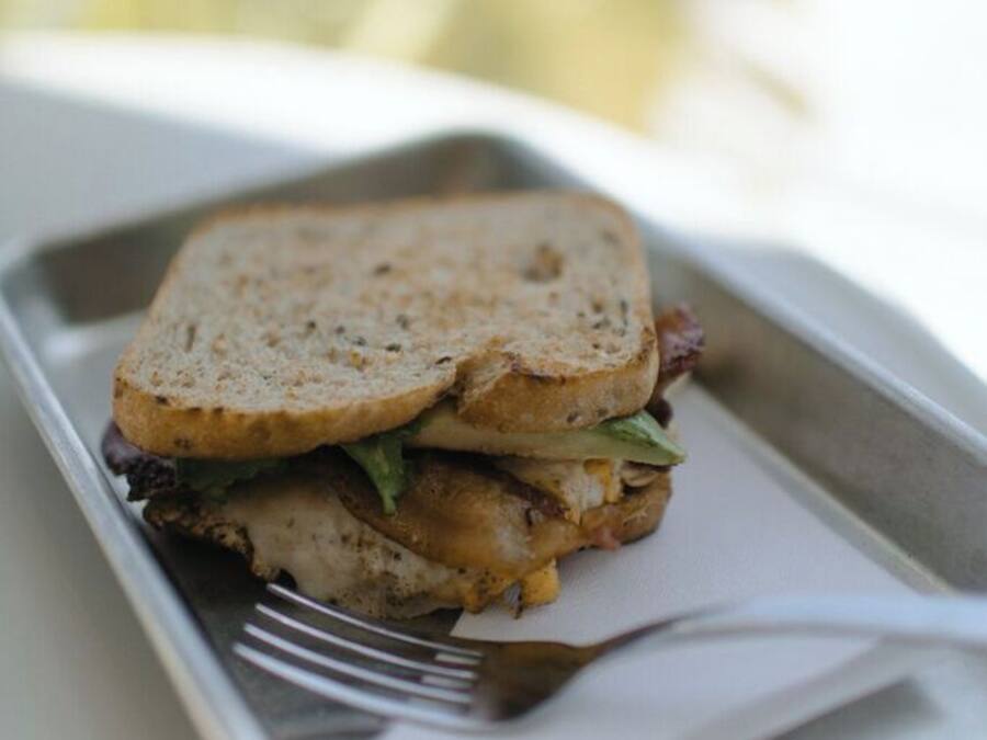 A sandwich on a tray with a fork, placed on a table.