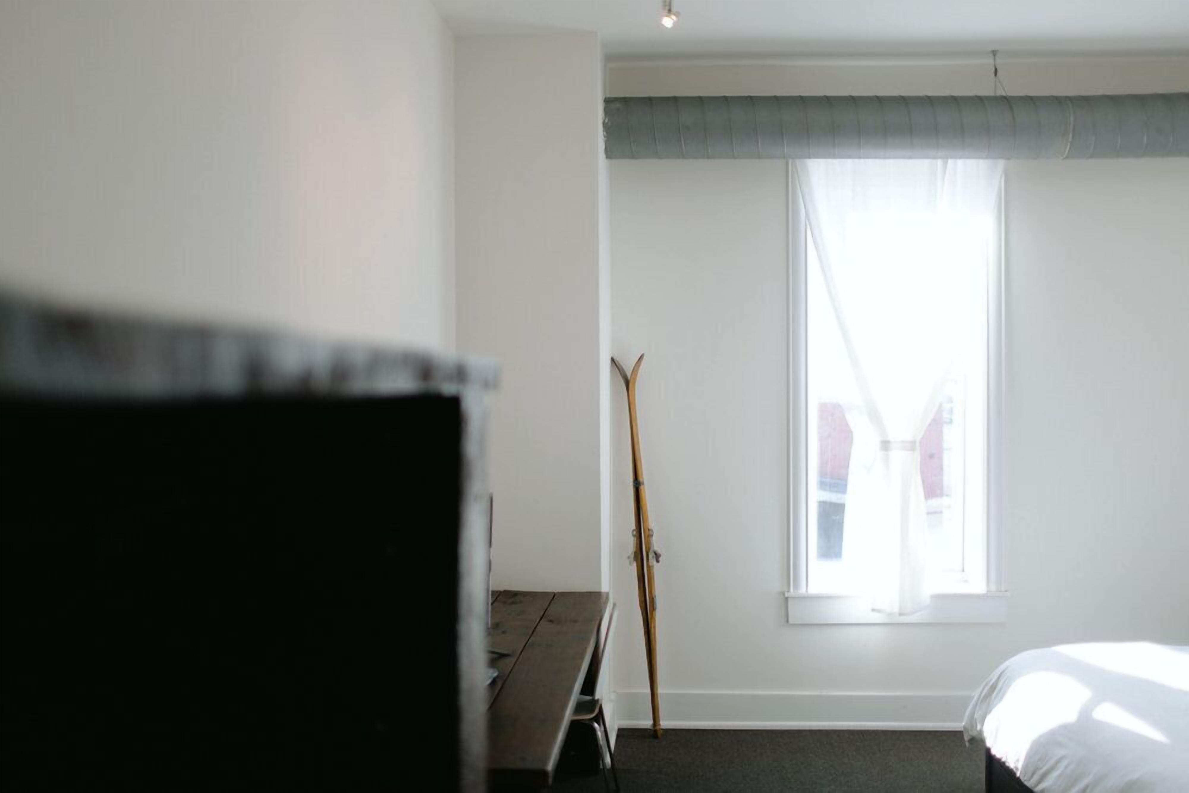 Habitació d'hotel amb llit, escriptori i finestra amb cortines.
