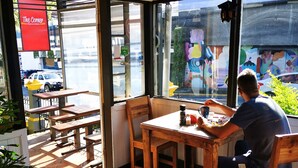 En restaurant med udendørs siddepladser, et synligt skilt med udgang og udsigt til gaden.