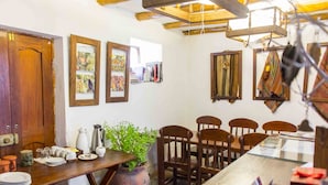 A dining area with wooden furniture, a large table, chairs, a potted plant, and framed artwork on the walls. - Casa Patacalle Bed & Breakfast Hotel (Ollantaytambo)