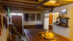 A traditional room with a wooden table, a fireplace, and various wall decorations. - Casa Patacalle Bed & Breakfast Hotel (Ollantaytambo)