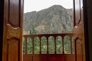 A view through a wooden door with a balcony, overlooking a mountainous landscape with terraced structures. - Casa Patacalle Bed & Breakfast Hotel (Ollantaytambo)