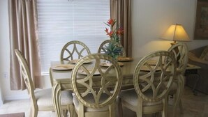 A dining area with a round table and six chairs, each with a decorative backrest. - Beautiful Vacation Home fully equipped (Haines City)