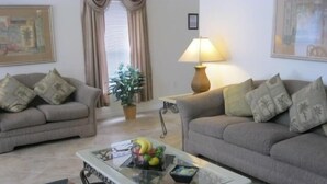 A living room with two sofas, a glass coffee table, a lamp, and a potted plant. - Beautiful Vacation Home fully equipped (Haines City)