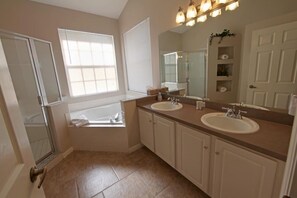 A bathroom with two sinks, a large mirror, and a walk-in shower. - Luxury Home Close by Theme Parks (Haines City)