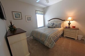 A bedroom with a bed, bedside table, lamp, dresser, and a window with curtains. - Luxury Home Close by Theme Parks (Haines City)