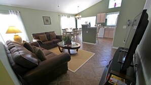 Ein Wohnzimmer mit einem braunen Ledersofa, einem Couchtisch und einem Fernseher-Möbelstück.