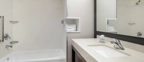 A modern bathroom with a bathtub, a sink, and a large mirror.