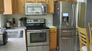 Une cuisine équipée d’appareils électroménagers en acier inoxydable, de meubles de rangement en bois, d’un four à micro-ondes, d’une cuisinière et d’un réfrigérateur.