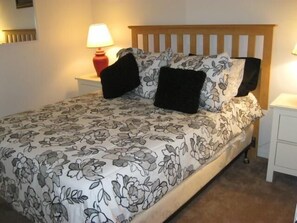 A neatly made bed with floral bedding, a wooden headboard, and two bedside tables with lamps. - Comfortable Villa Close by Theme Parks (Haines City)