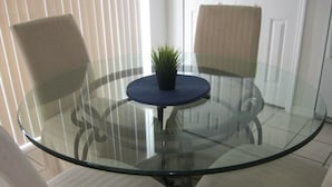 A glass-top round table with a small potted plant, two chairs, and a white door in the background. - Lovely Home Perfect for a Family (Haines City)