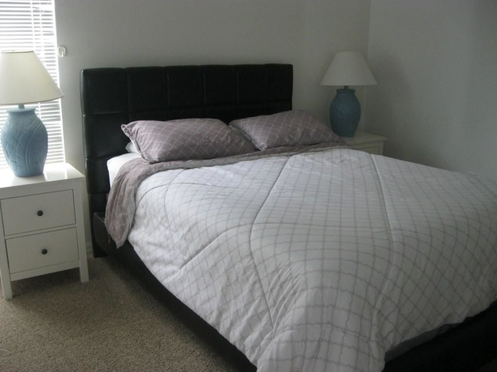 A bedroom with a bed, two nightstands, and lamps.
