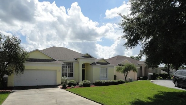 A residential house with a garage, a well-maintained lawn, and a driveway. - Very Comfortable Villa Fully Equipped (Haines City)