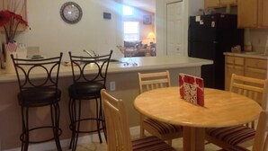 A compact kitchen with a central island, wooden chairs, and a round table. - Amazing Home with Golf Course View (Haines City)