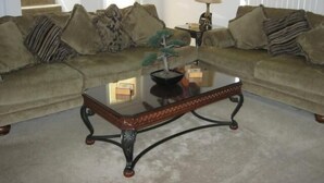 A living room with a sofa set, a coffee table, and a staircase in the background. - Amazing Villa at an Exceptional Price (Haines City)