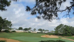 A golf course with sand bunkers, a clubhouse, and surrounding trees. - Luxury Villa near Theme Parks (Haines City)