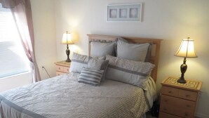 A bedroom with a large bed, two bedside tables with lamps, a wooden headboard, and a small dresser. - Luxury Villa near Theme Parks (Haines City)