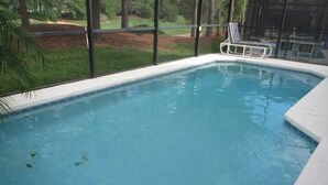 A swimming pool with clear blue water, surrounded by a white deck and a glass enclosure. - Luxury Villa near Theme Parks (Haines City)