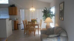 A living room with a sofa, a dining table with chairs, a lamp, and a plant. - Very Comfortable Villa Fully Equipped (Haines City)