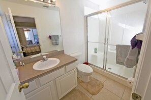 A bathroom with a sink, toilet, and glass shower enclosure.