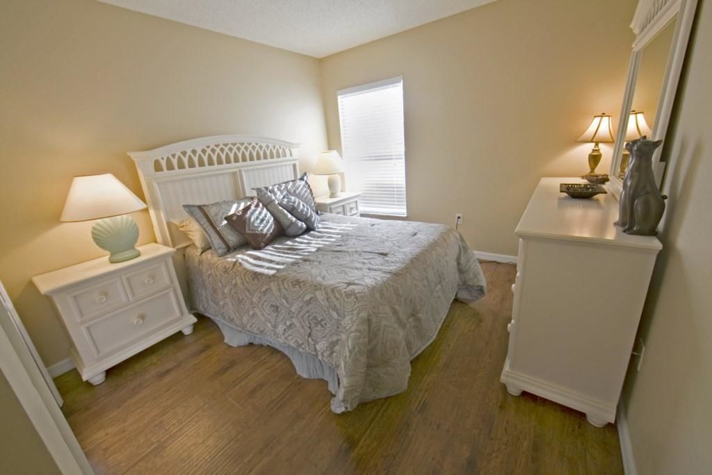 A bedroom with a bed, nightstands, a dresser, and a window with blinds.
