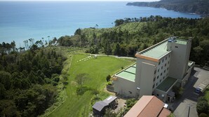 Een hotel met een groot groen gazon, een tennisbaan en uitzicht op de oceaan.