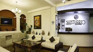 Un vestíbulo de hotel con una recepción, sofás, una mesa de centro y un televisor.