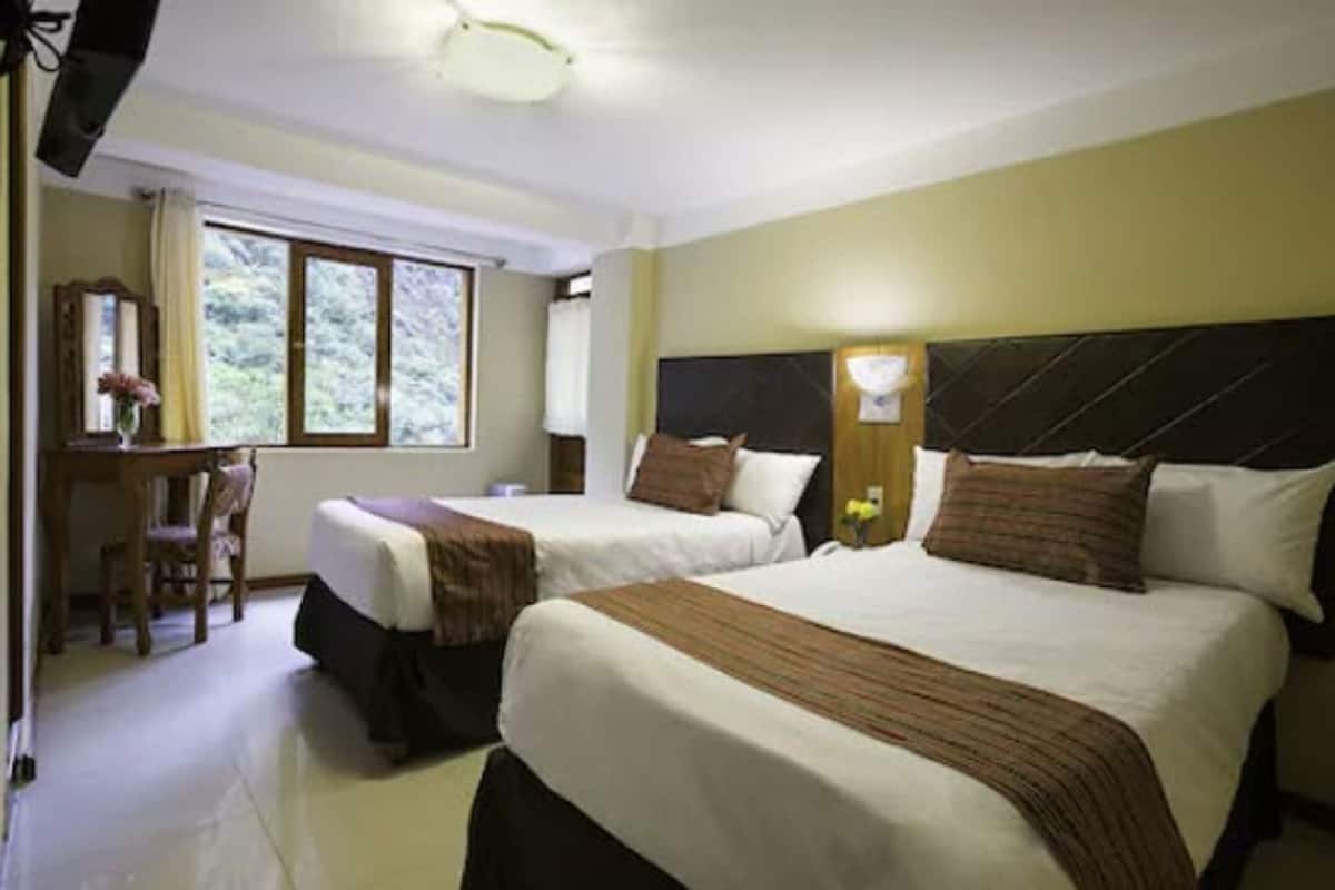 Habitación de hotel con dos camas, un escritorio y una silla.