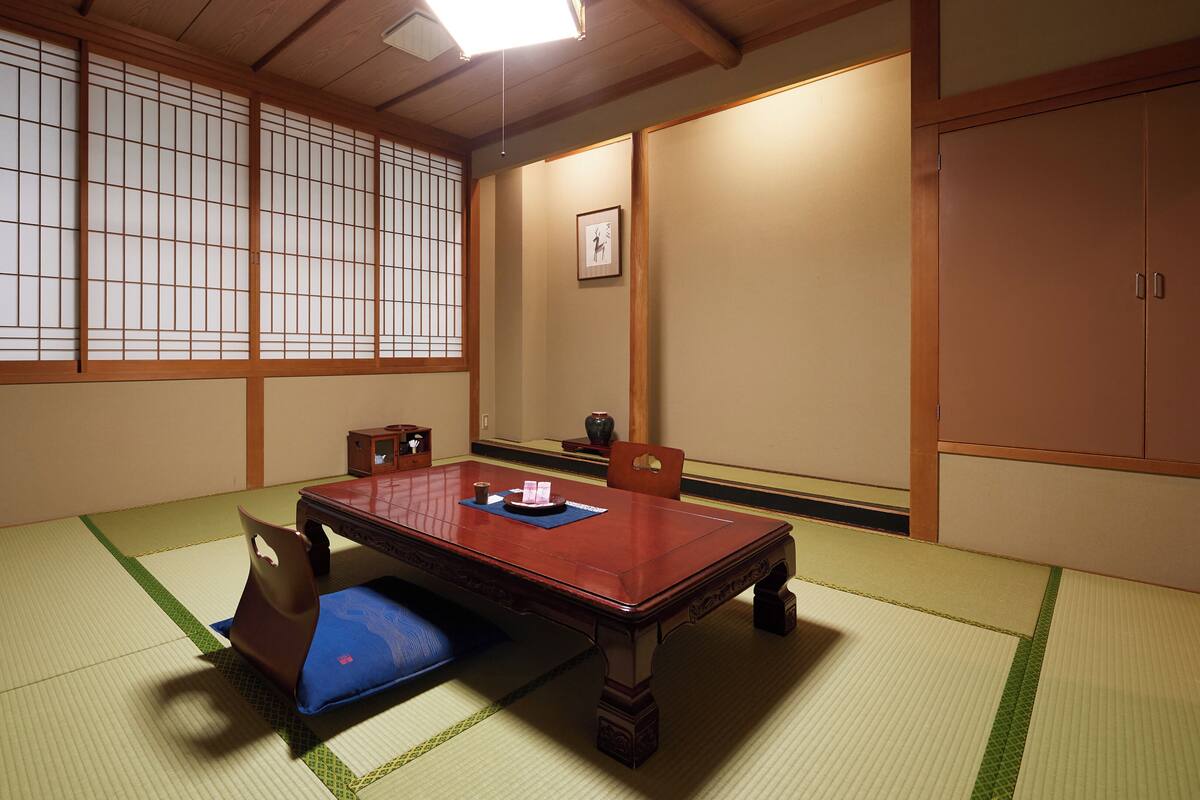 Une pièce de style japonais traditionnel, avec un sol recouvert de tatamis, une table basse et des portes coulissantes.