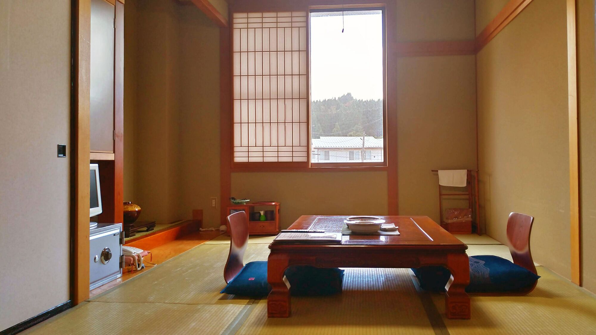 Una habitación japonesa tradicional con suelo de tatami, una mesa de madera baja y puertas correderas shoji.