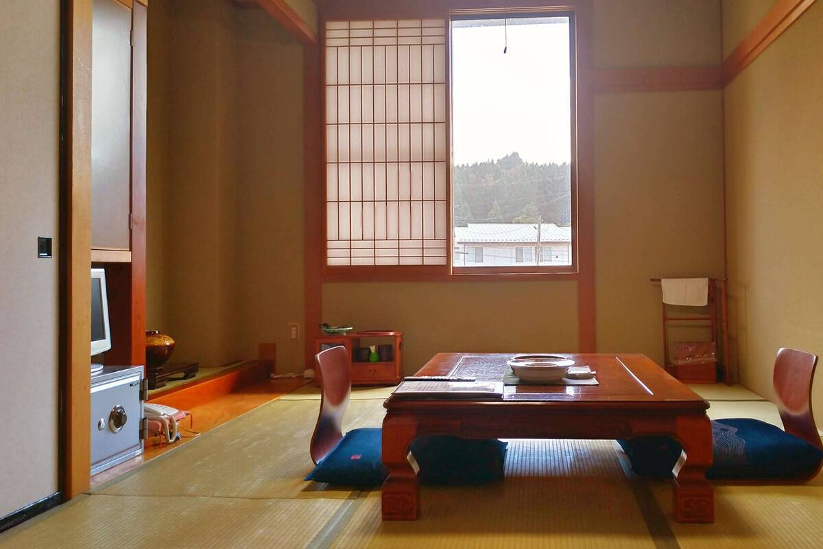 Une pièce de style japonais traditionnel, avec un sol recouvert de tatamis, une basse table en bois et des portes coulissantes en papier de riz (shoji).