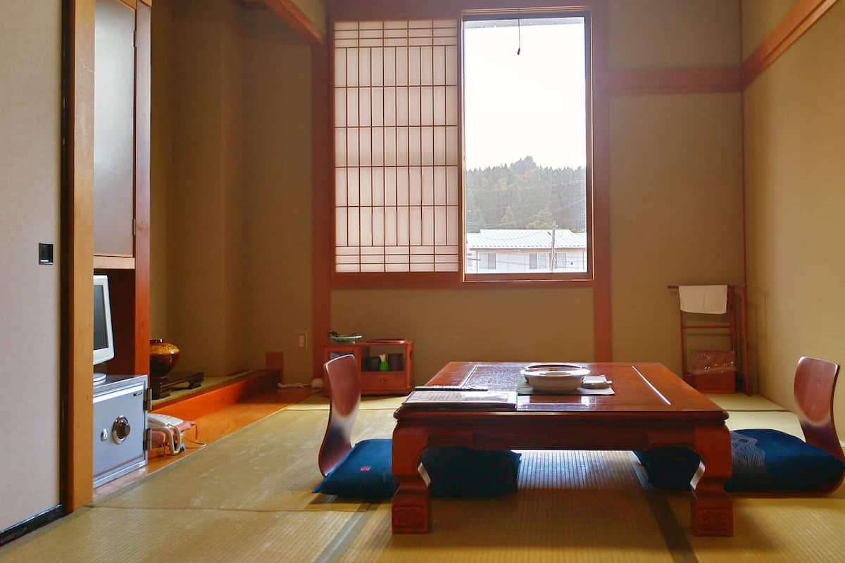 Una habitación japonesa tradicional con suelo de tatami, una mesa de madera baja y puertas correderas shoji.