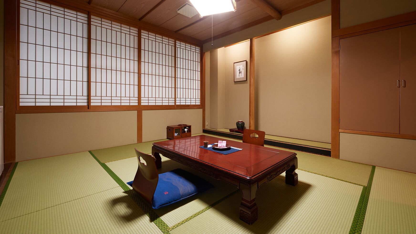 Una habitación japonesa tradicional con suelo de tatami, una mesa baja y puertas correderas.