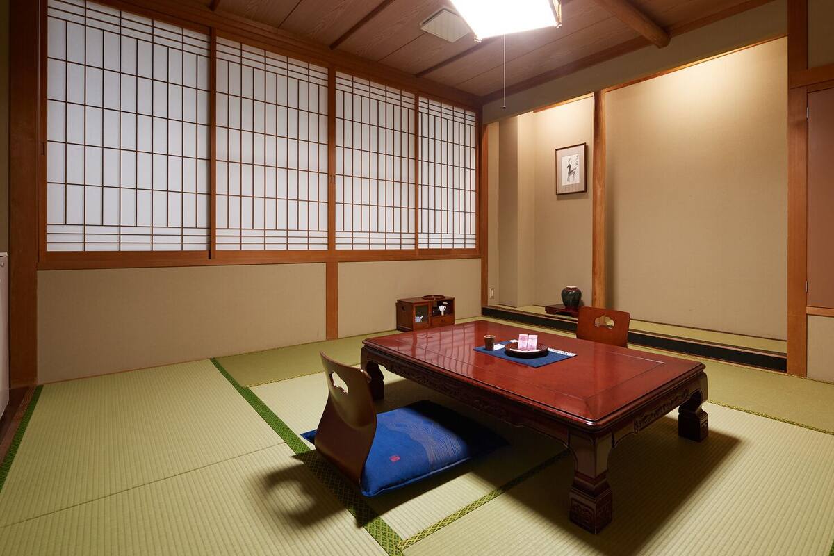 Une pièce de style japonais traditionnel, avec un sol recouvert de tatamis, une table basse et des portes coulissantes.